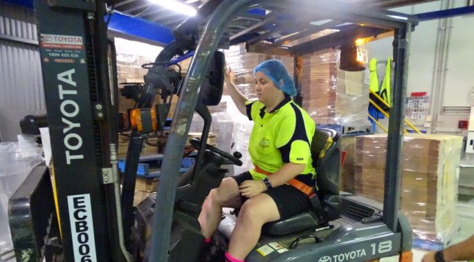 Women in manufacturing - driving a forklit in a busy warehouse