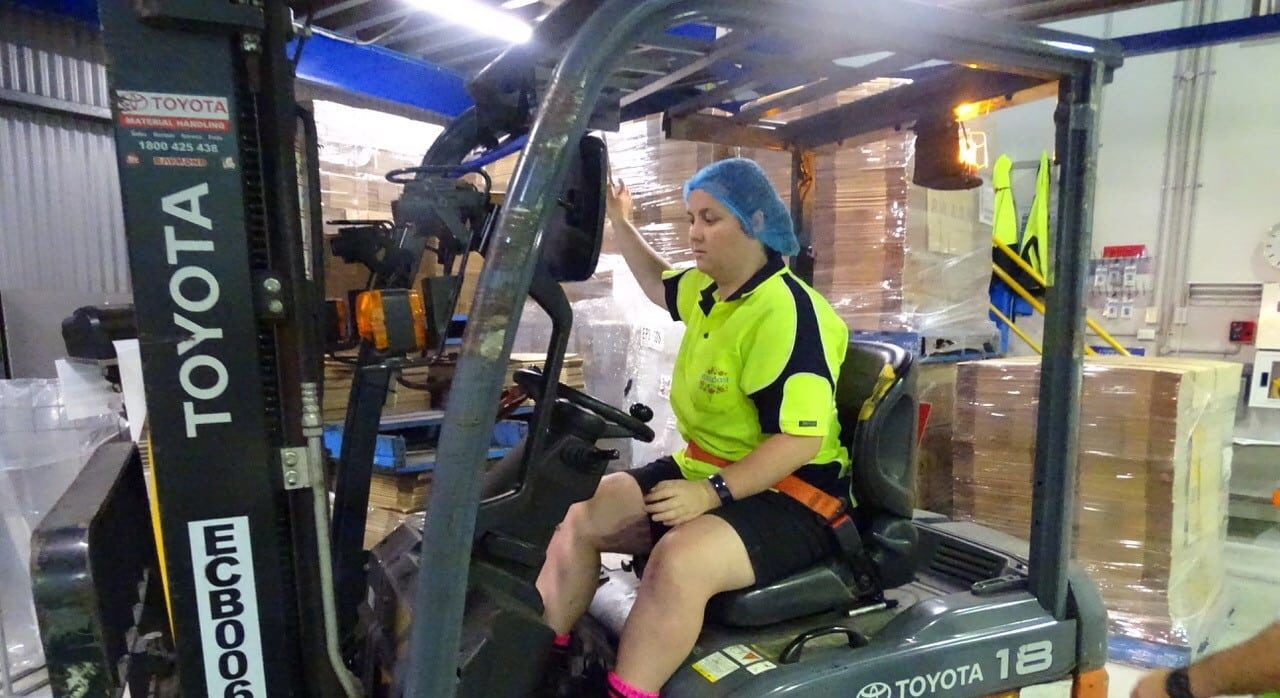 Women in manufacturing - driving a forklit in a busy warehouse